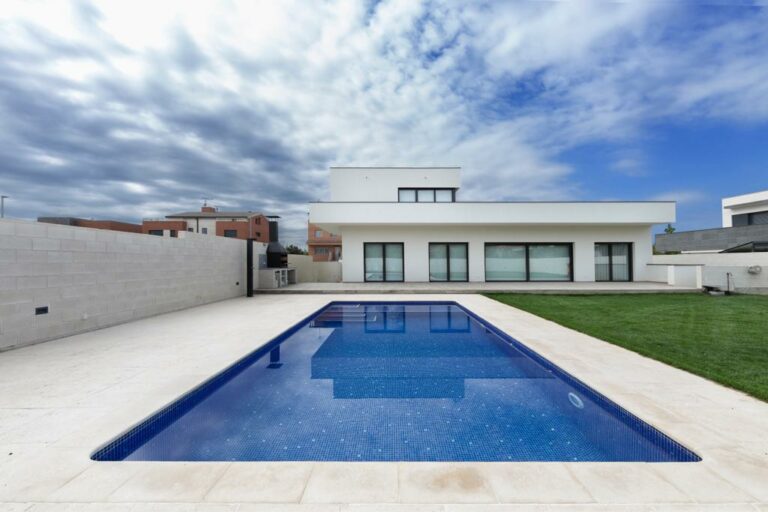 Piscina rectangular junto a una vivienda y su jardín